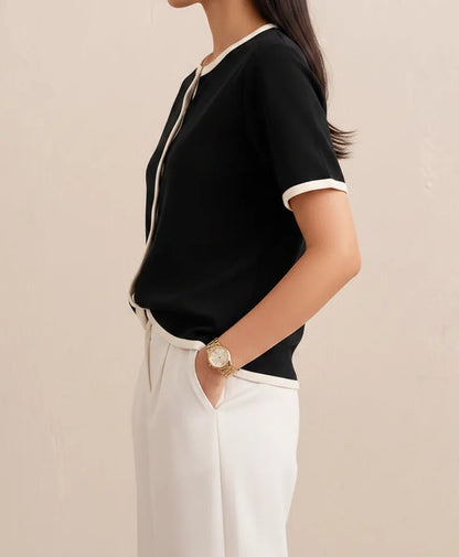 Black fitted short-sleeve top with white-trimmed neckline and button placket, side view