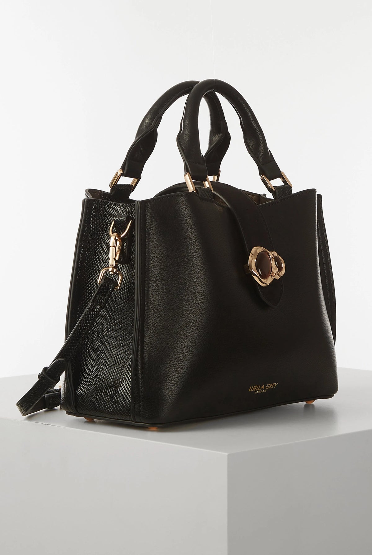 Black handbag with crossbody strap, gold-tone zippers, and clover front clasp