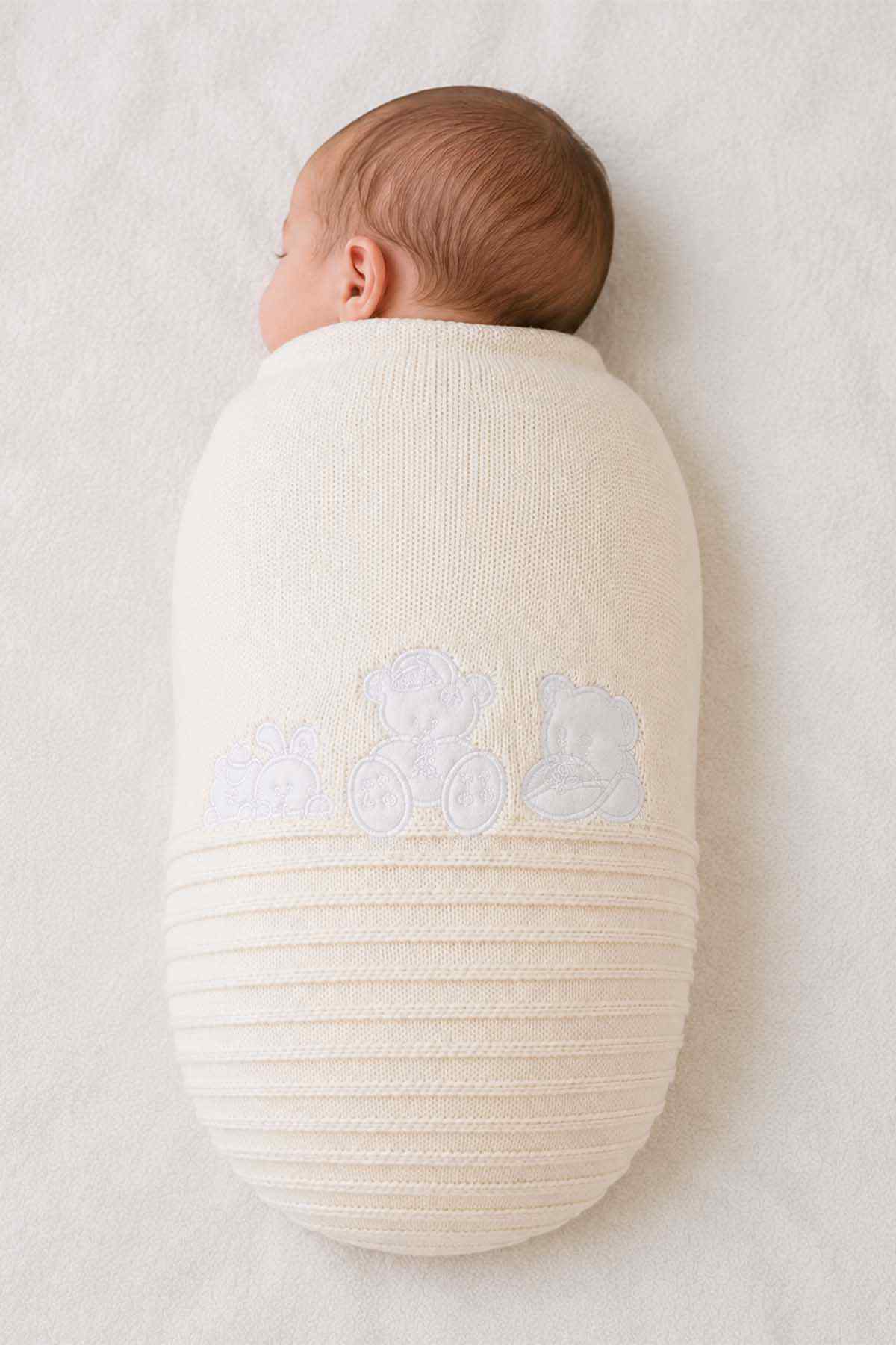 Cream baby shawl wrap worn on newborn, with teddy bear applique and stripes