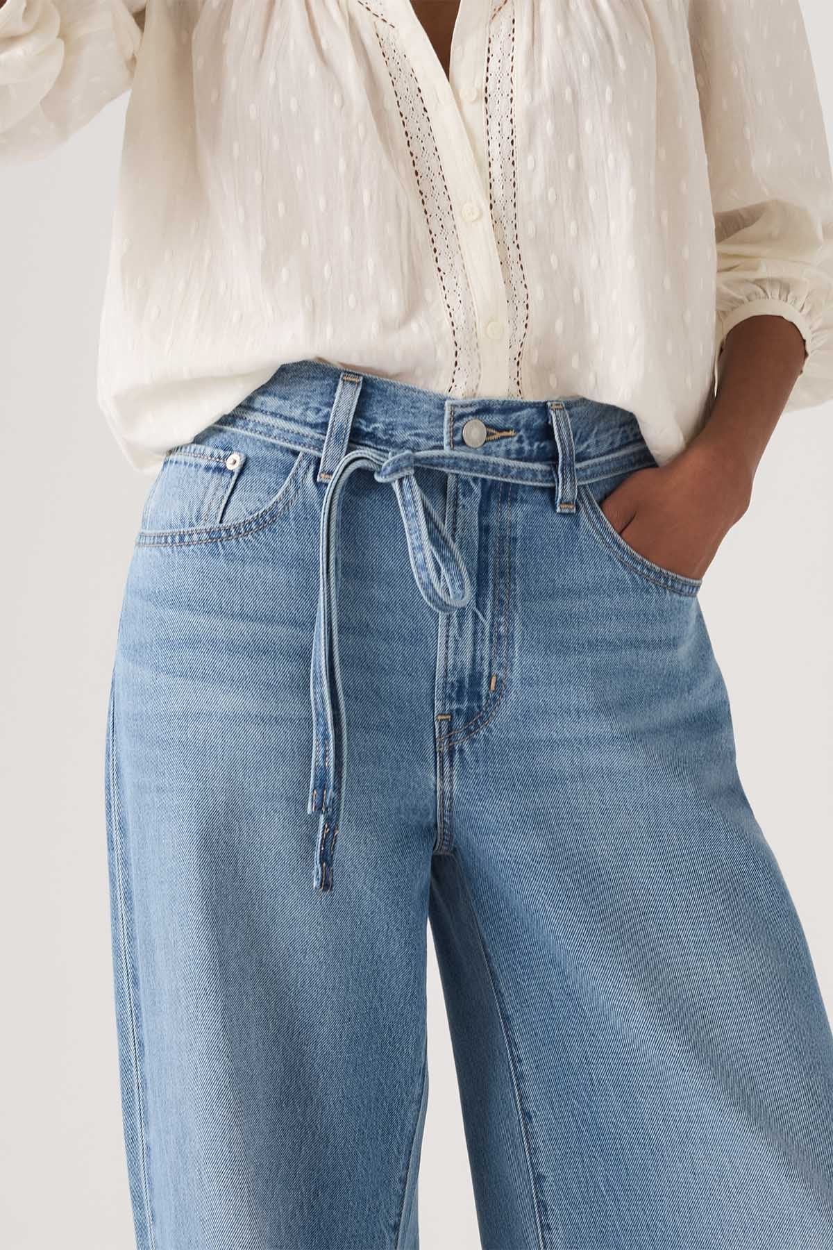Levi's medium indigo wide-leg jeans close-up: zip fly, tie waist, front pockets