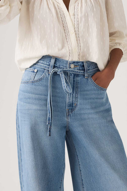 Levi's medium indigo wide-leg jeans close-up: zip fly, tie waist, front pockets