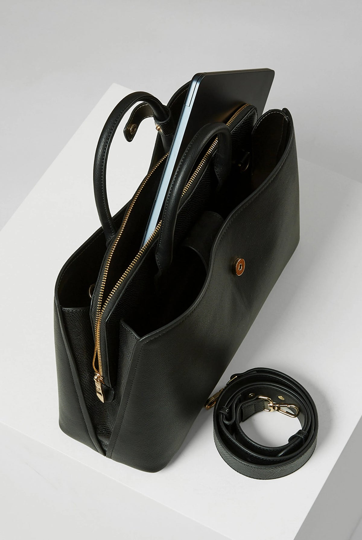 Black handbag with interior zip compartments and detachable crossbody strap, gold hardware
