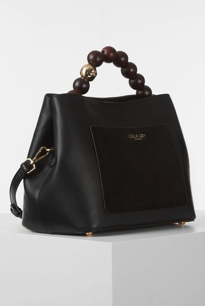 Black handbag with brown bead top handle, gold clasp, and front logo patch