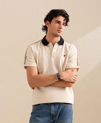 Fitted off-white polo shirt with navy collar and side sleeve stripe; small chest logo.