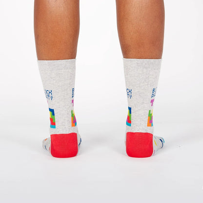 Light gray crew socks with colorful pixel blocks and red heel, view from back