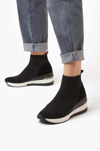 Black knit ankle boots on model with rolled denim cuffs and white platform sole