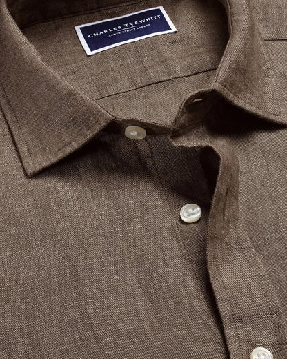 Brown button-up shirt collar with brand label and white button placket