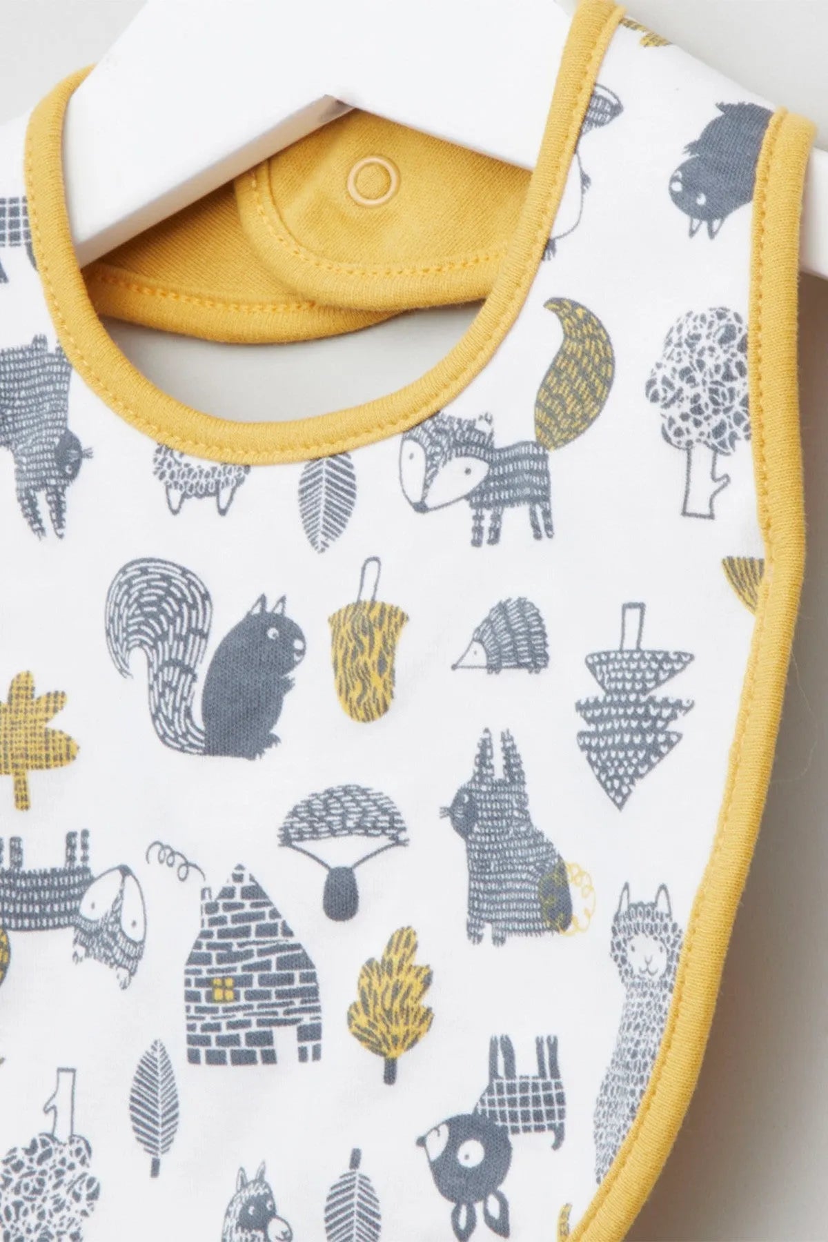 Baby bib close-up with animal icons on white, yellow edging and snap