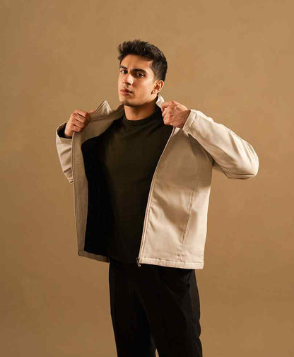 Beige zip-up jacket with stand collar, hands in sleeves, fitted silhouette