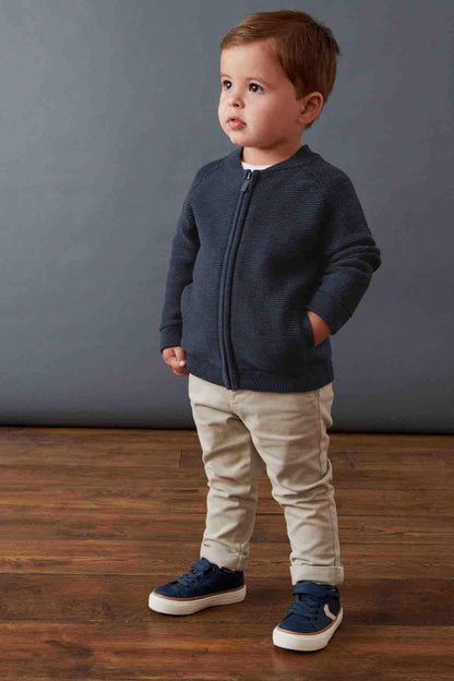 Navy zip-up knit jacket with long sleeves and front zipper; paired with light pants