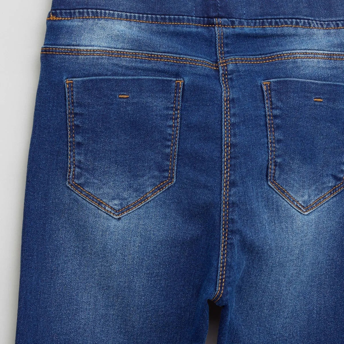 BABYSHOP blue denim jeans close-up: rear pockets with orange topstitch