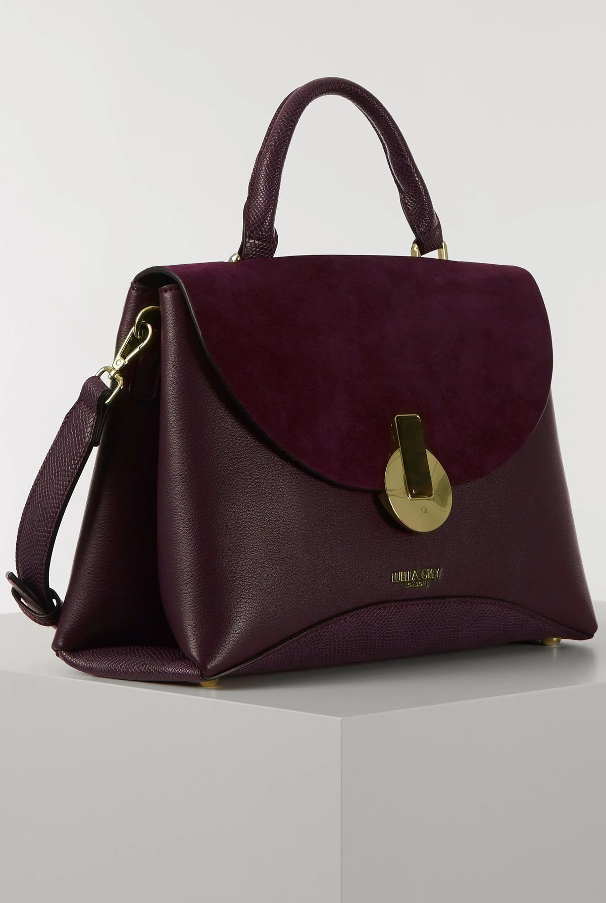 Purple structured handbag with curved flap, gold-tone clasp, and side zipper