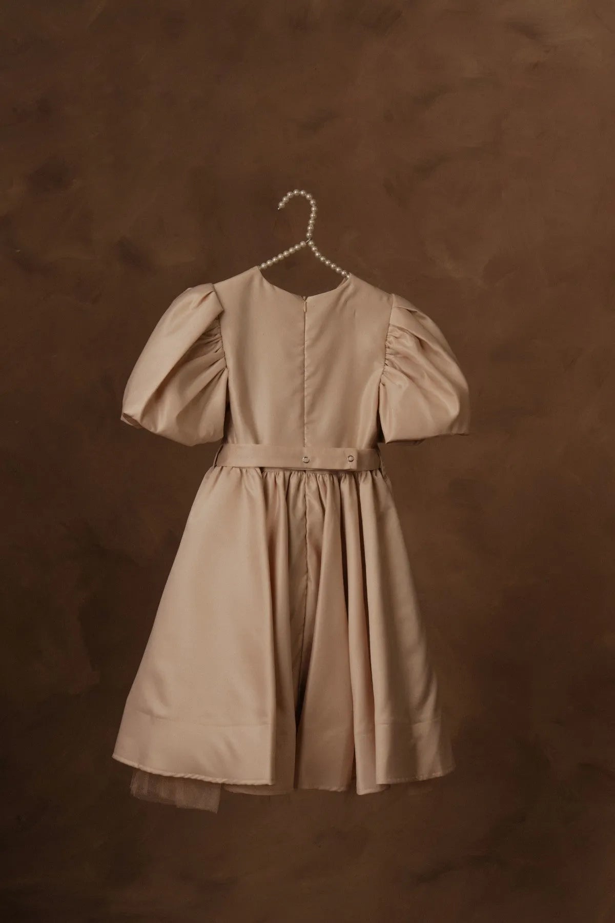 Beige puff-sleeve dress with pleated skirt and waist tie on hanger