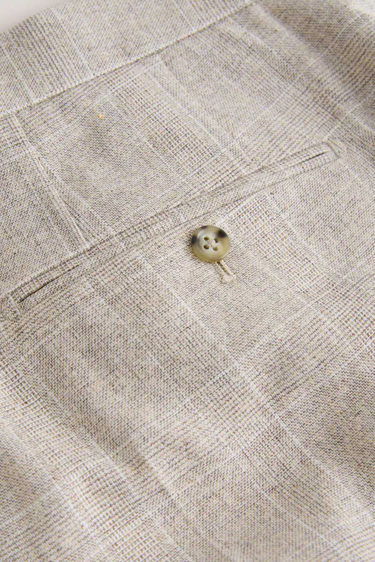 Light beige trouser cuff with small round button and stitched placket