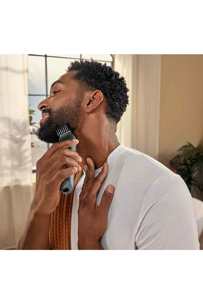 Black electric beard trimmer held against beard for trimming