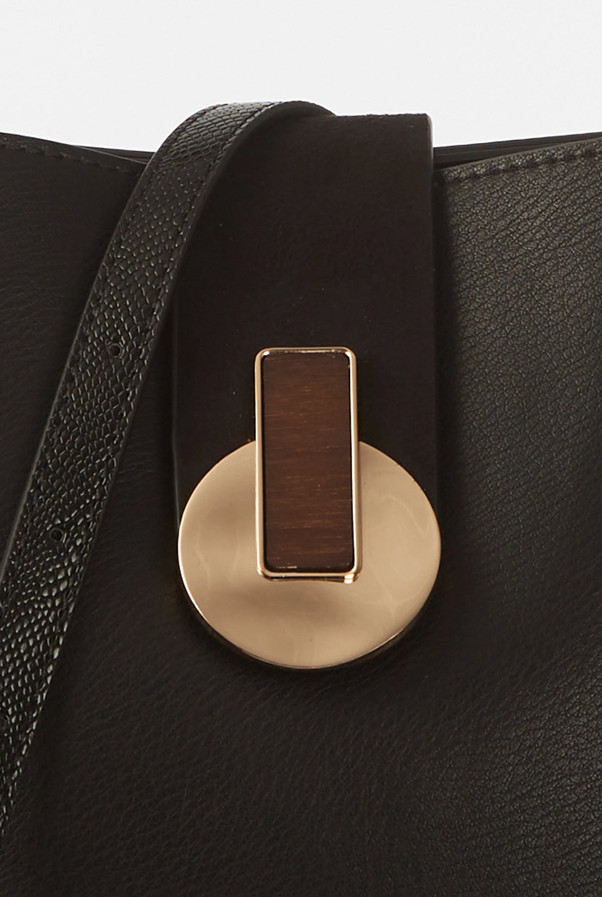Close-up of gold-tone front clasp on black textured handbag