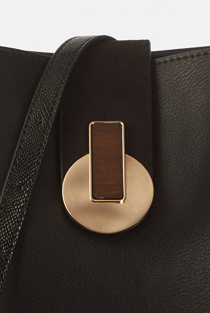 Close-up of gold-tone front clasp on black textured handbag