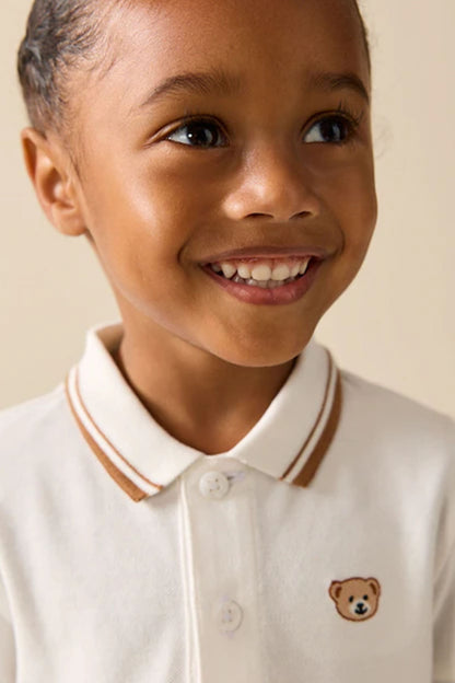 Children's white polo shirt with brown-striped collar and teddy bear chest patch