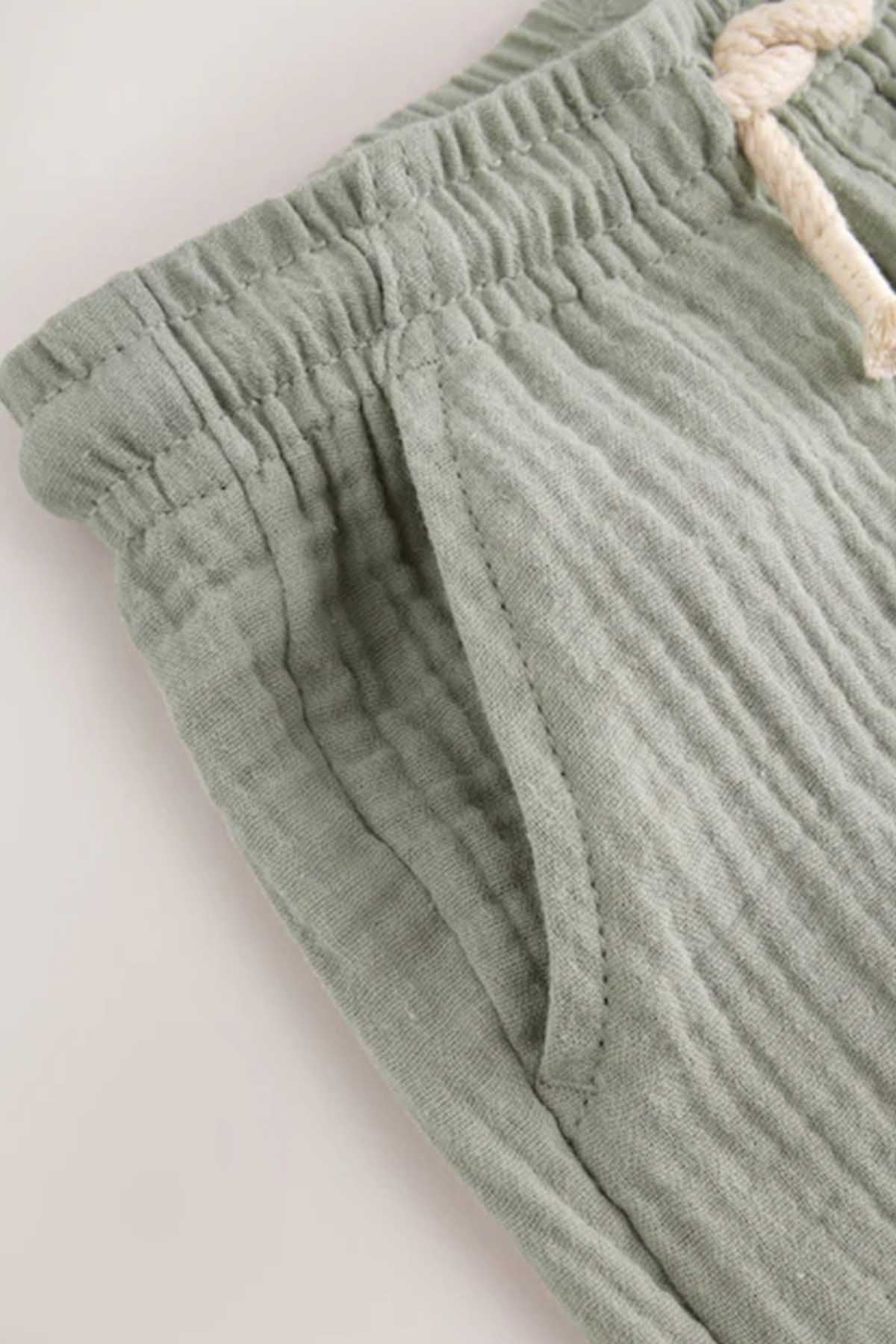 Sage green elastic-waist shorts with gathered detailing, close-up