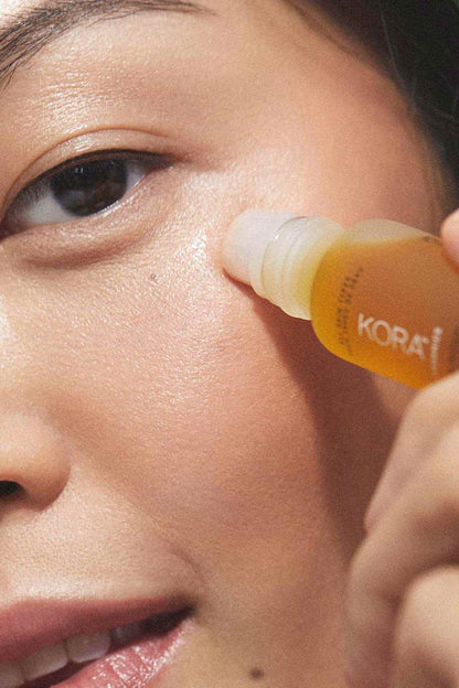 Kora Organics eye oil dropper applying amber oil near eye
