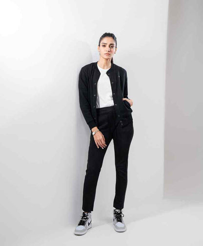 Black fitted button-front jacket with long sleeves and chest logo, full-length view on model