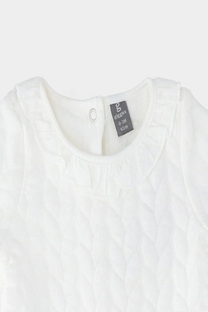 Cream baby dress neckline with small keyhole button and textured fabric
