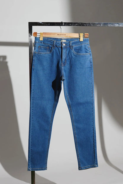 Blue denim jeans on hanger with zip fly, belt loops, and front pockets