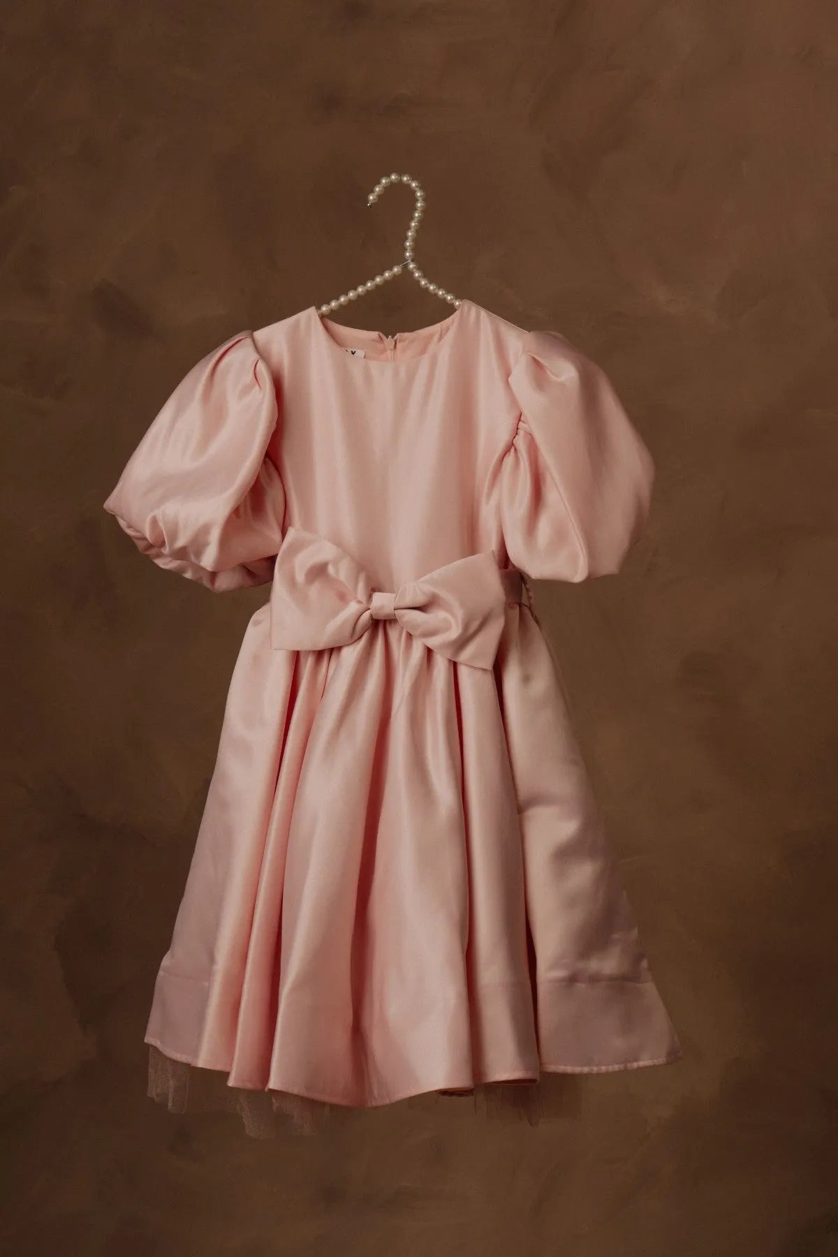 Pink puff-sleeve dress with waist bow and flared skirt, on pearl hanger.