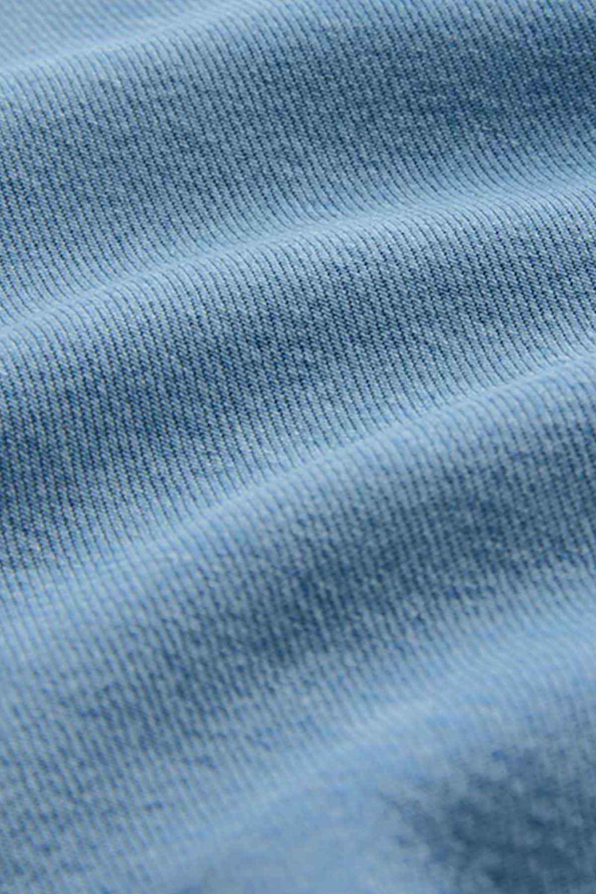 Mid blue denim fabric texture close-up with fine woven pattern