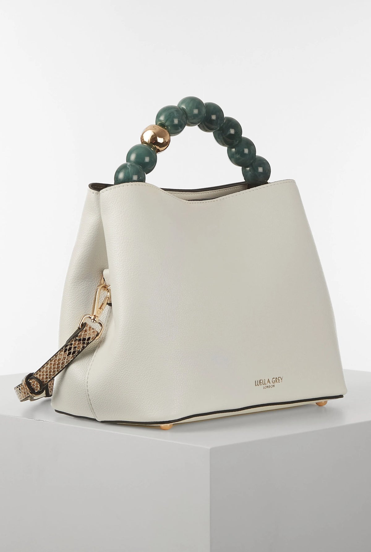White bucket bag with green beaded handle and leopard-print strap detail; curved silhouette