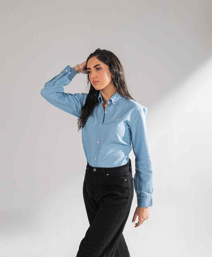 Fitted light blue button-up shirt with long sleeves and black jeans