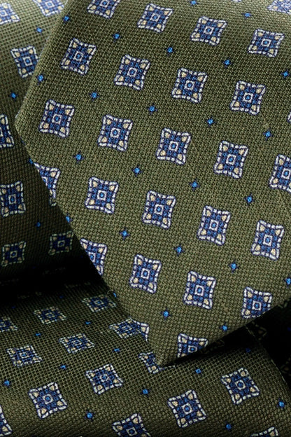 Green tie close-up with repeating blue geometric squares pattern