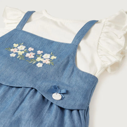 Blue denim romper detail with floral embroidery, button closure, and adjustable strap