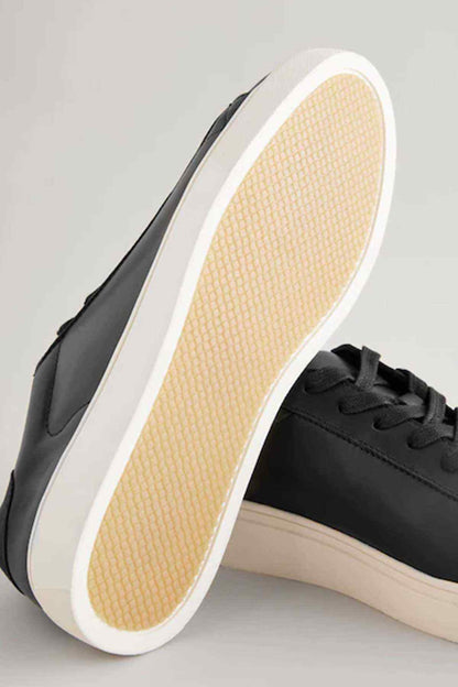 Black lace-up sneaker outsole view with white midsole and textured sole