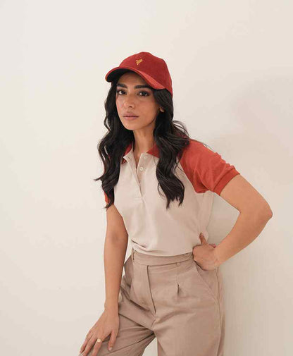Fitted polo shirt with red sleeves; khaki trousers, red baseball cap with logo