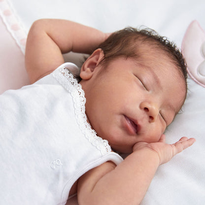 White baby bodysuit with lace trim, worn on infant