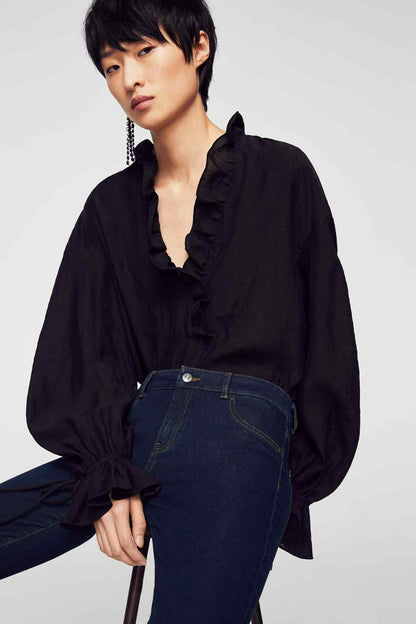 Dark blue slim-fit jeans with front pockets and belt loops, with dark blouse