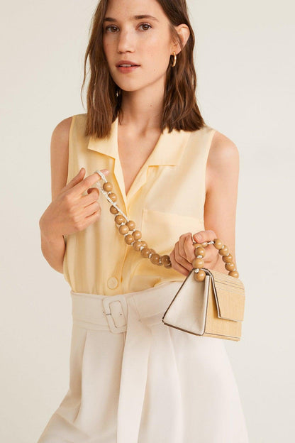 Vanilla sleeveless button-front blouse with collar, chest pockets, and belt
