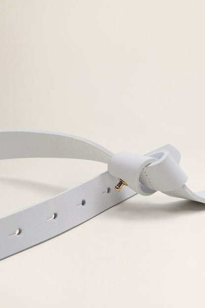 White belt detail with T buckle, gold pin, and adjustable holes