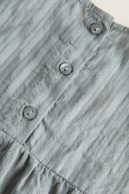 Grey pinstriped blouse close-up with three front buttons and gathered lower panel