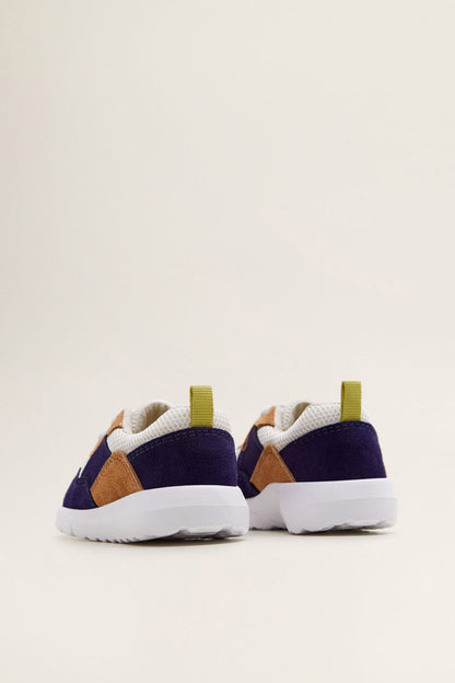 Navy lace-up sneakers with tan heel panels, white sole, and yellow pull tab