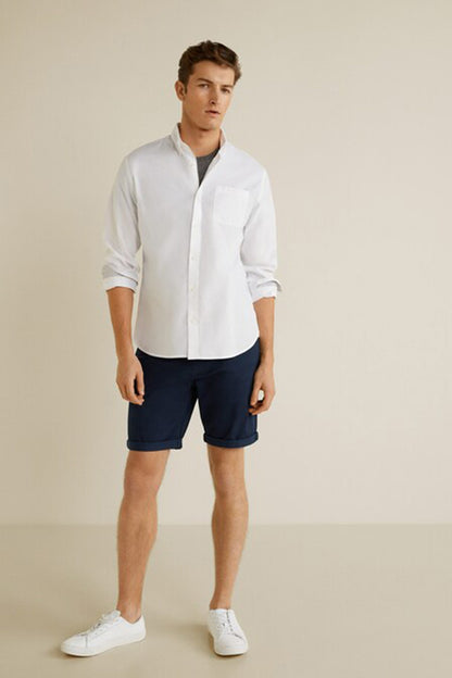 Navy shorts worn with a white button-up shirt, knee length