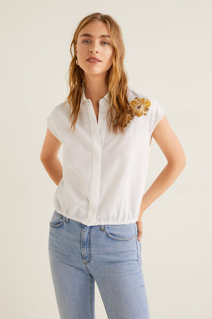 White embroidered short-sleeve blouse with floral accents and button-front