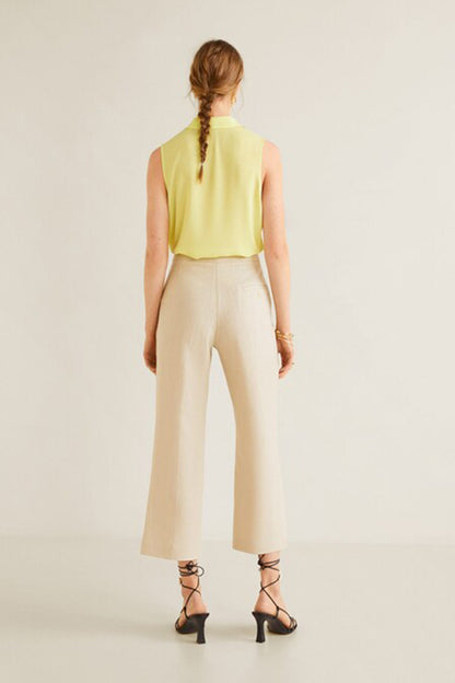 Back view of lime sleeveless collared blouse with light beige wide-leg trousers