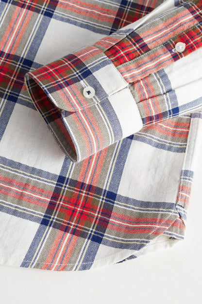 Plaid shirt cuff detail with button and striped fabric in white, red, and blue
