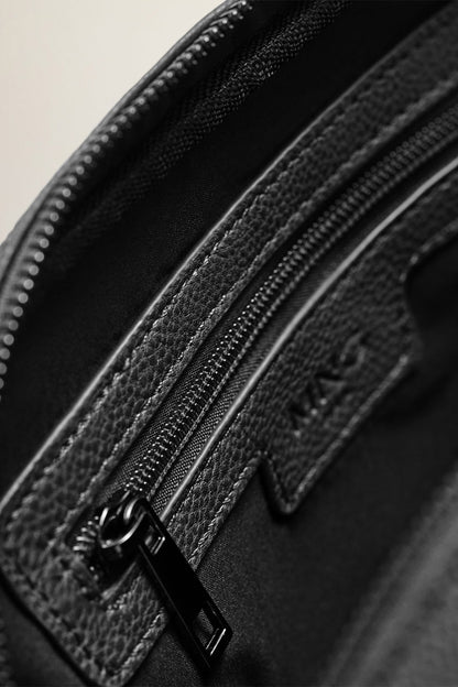 Black pebbled leather bag close-up with double zippers and stitched logo