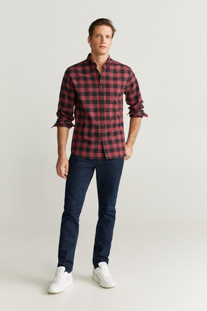 Red and dark blue plaid button-up shirt with long sleeves worn with jeans