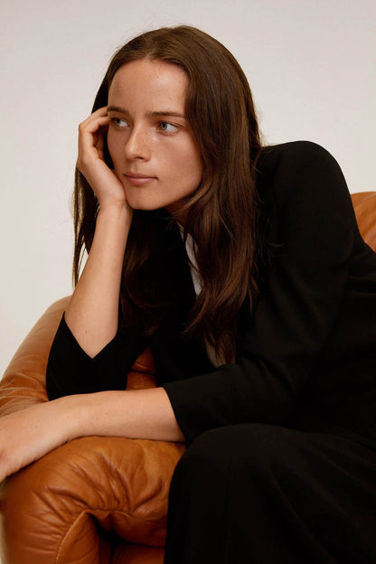 Black blazer close-up with notched lapel and long sleeves, worn with matching trousers