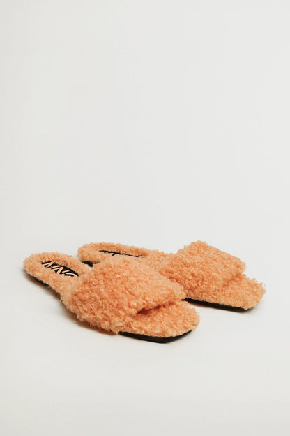 Pair of peach teddy slip-on slippers with flat sole and logo strap