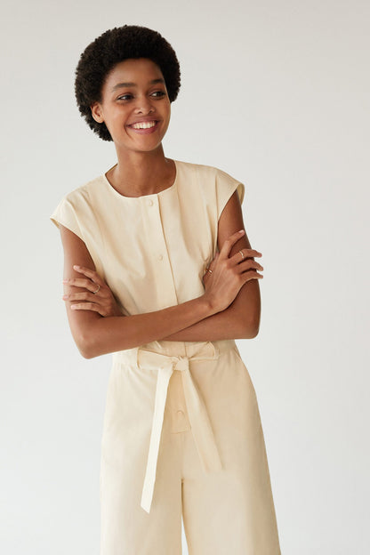 Cream pastel jumpsuit with cap sleeves, front buttons, and tie waist